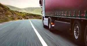 Red lorry driving down a mountain road