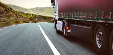 Red lorry driving down a mountain road