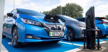 Blue car charging up at public charging point