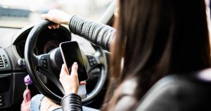 Woman looking at her mobile phone while driving