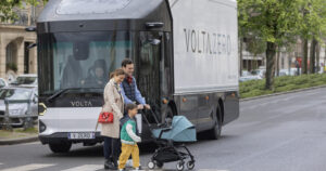 Young family crossing the road in front of a Volta Truck