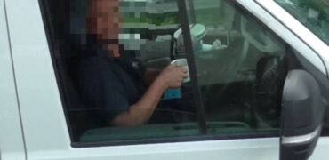 Driver drinking a mug of tea, no hands on the steering wheel