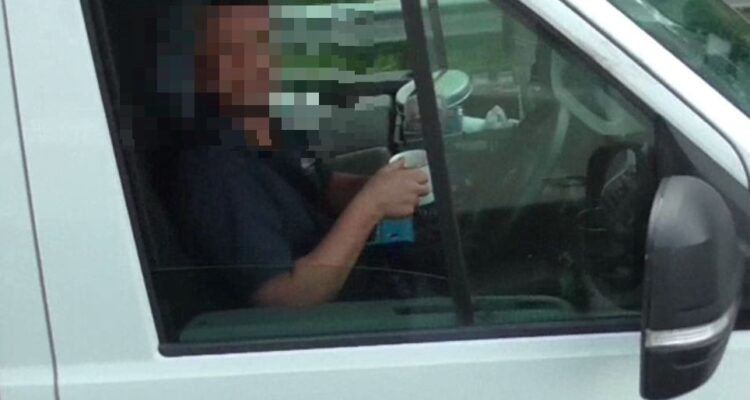 Driver drinking a mug of tea, no hands on the steering wheel