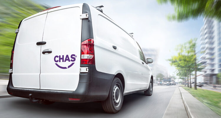 Rear view of a white CHAS van driving in a city. Motion blurred city background with buildings and trees.