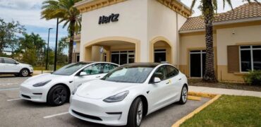 Two Tesla Y Models in front of an Hertz office