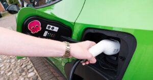 Green electric car being plugged in for charging