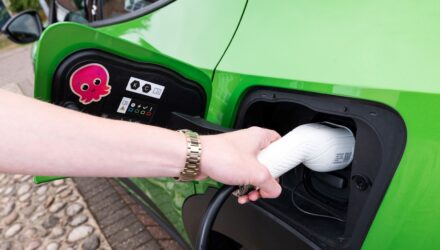 Green electric car being plugged in for charging