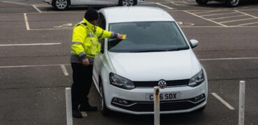 Parking attendant putting a ticket on a car in a carpark