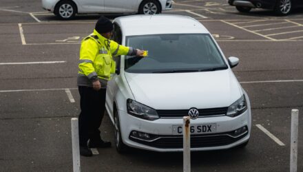 Parking attendant putting a ticket on a car in a carpark