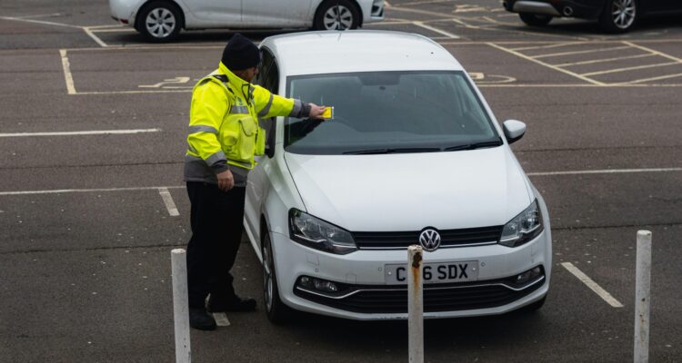 Parking attendant putting a ticket on a car in a carpark
