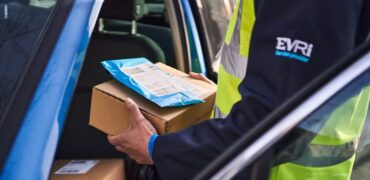 Courer outside blue van holding a box and packet