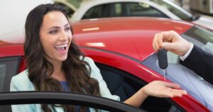 Young woman looking very happy getting the keys to her new car