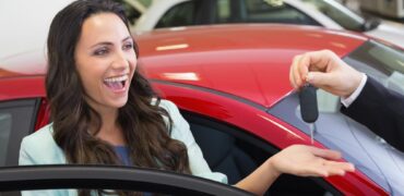 Young woman looking very happy getting the keys to her new car