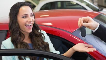 Young woman looking very happy getting the keys to her new car