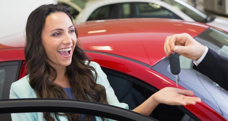 Young woman looking very happy getting the keys to her new car
