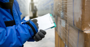Closeup shooting hand of worker with clipboard checking goods in freezing room or warehouse