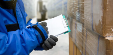 Closeup shooting hand of worker with clipboard checking goods in freezing room or warehouse