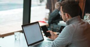 Man with laptop looking at his phone