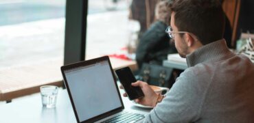 Man with laptop looking at his phone