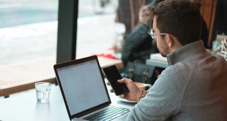 Man with laptop looking at his phone