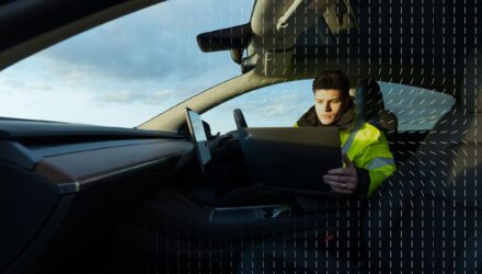 Thatcham Research specialist sitting in a car looking at a laptop