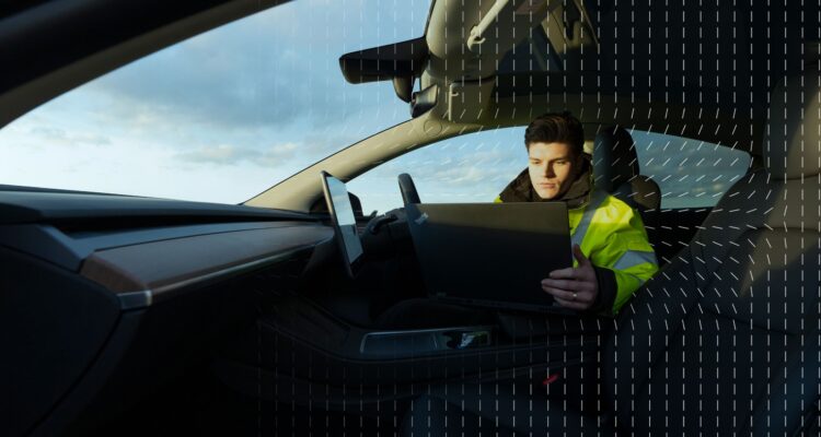 Thatcham Research specialist sitting in a car looking at a laptop