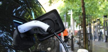 Electric vehicles charging station on a background of a row of vans