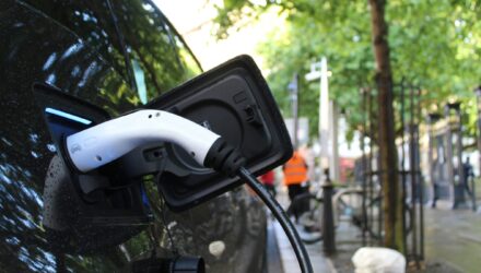 Electric vehicles charging station on a background of a row of vans