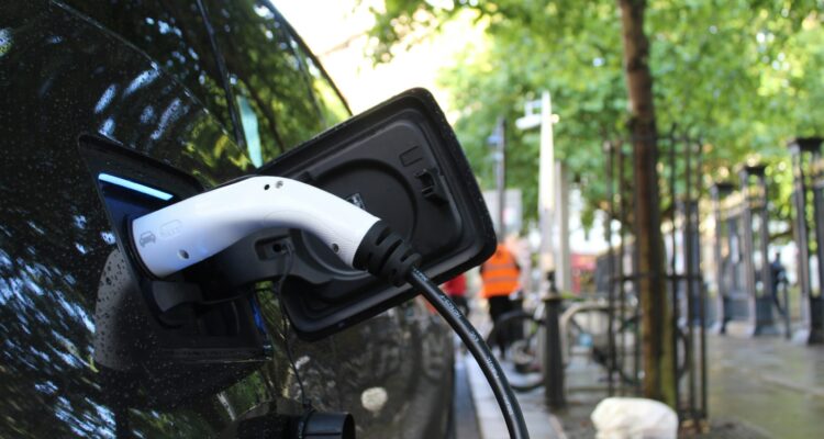Electric vehicles charging station on a background of a row of vans