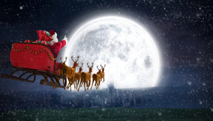 Santa in his sleigh flying towards a very bright full moon