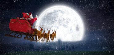 Santa in his sleigh flying towards a very bright full moon