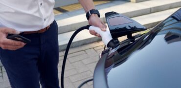 Driver plugging in a charging cable into his car