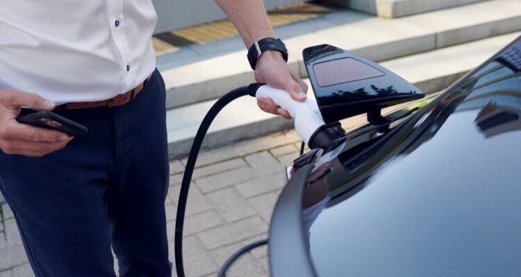 Driver plugging in a charging cable into his car